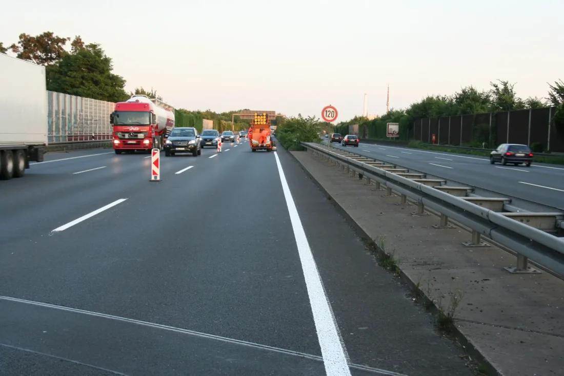 Markierungsarbeiten auf einer befahrenen Autobahn. Die Fahrspur ist abgesperrt.